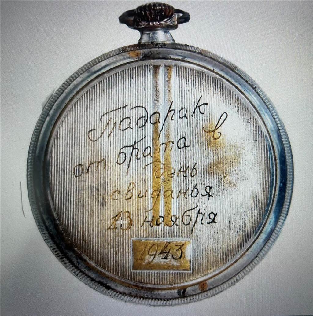 Eine Taschenuhr mit Gravur in kyrillischer Schrift.