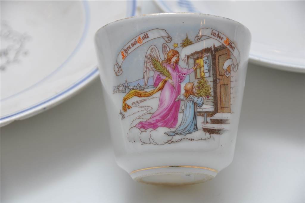 Weihnachten im Museum: Als es Bescherung nur in bürgerlichen Familien gab Eine Weihnachtstasse aus den 1920er Jahren zeigt das Christkind mit einem Engel vor einem verschneiten Haus.