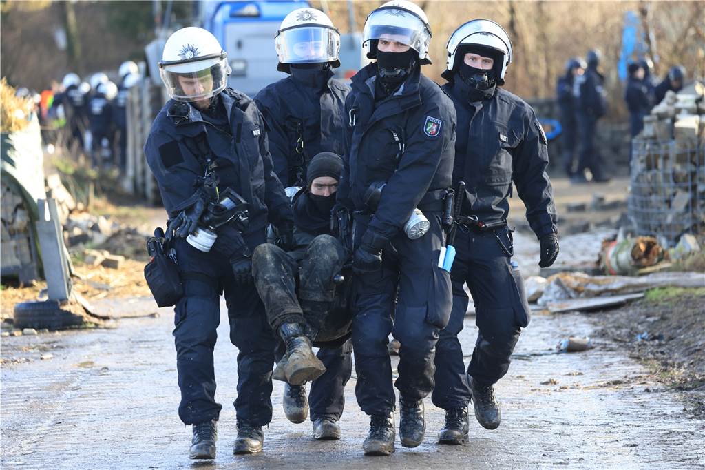 So war der erste Räumungstag in Lützerath: Überwiegend friedlicher Protest Polizisten tragen einen Klimaaktivisten vom besetzten Braunkohleort Lützerath weg.