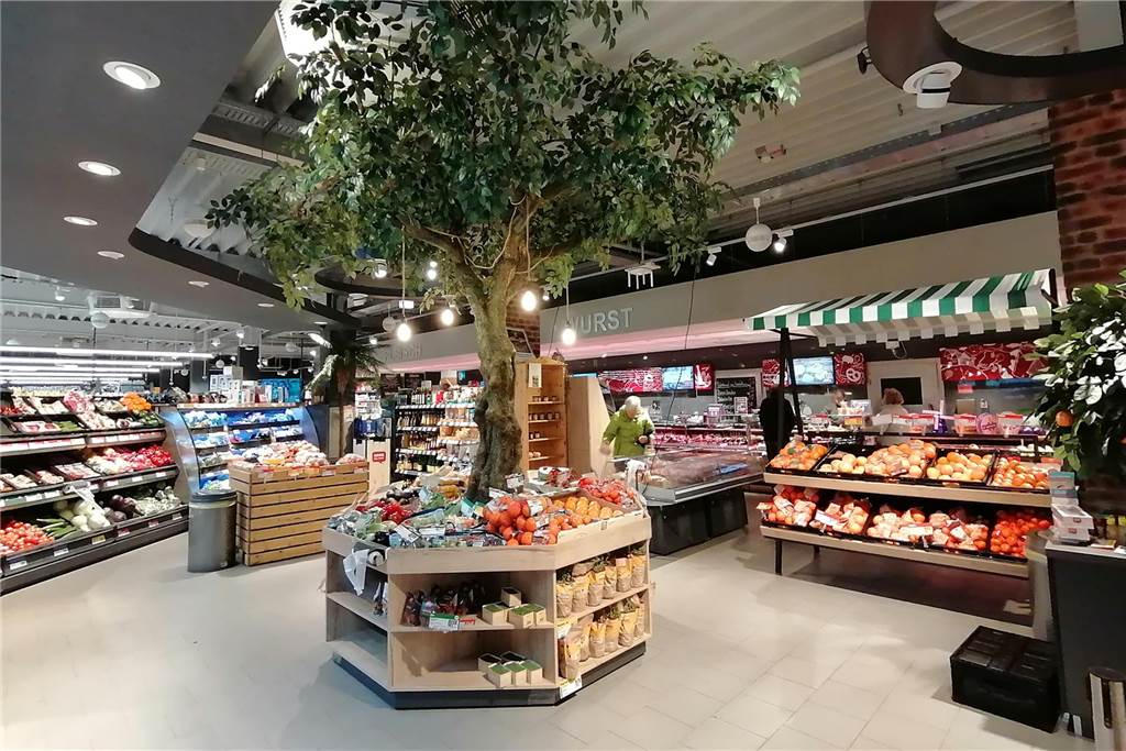 Rewe Teupe in Bodelschwingh: Jetzt wieder mit Lotto und Post Die neu gestaltete Obst- und Gemüseabteilung des Marktes mit einem Baum und einem Marktstand