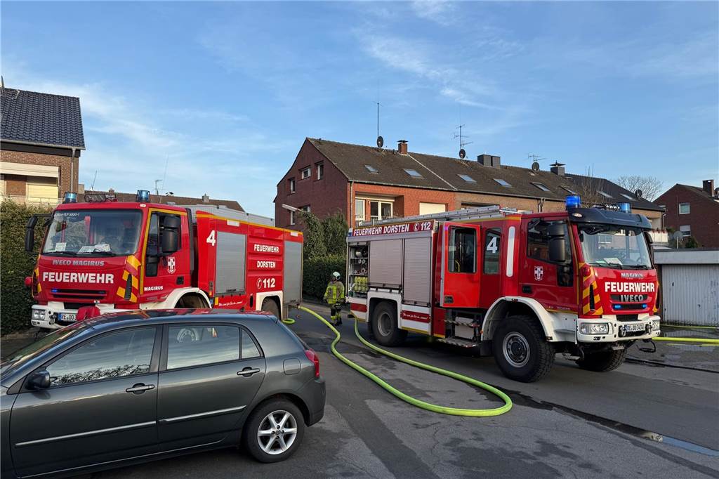Zwei Feuerwehrfahrzeuge stehen vor einem Wohnhaus.