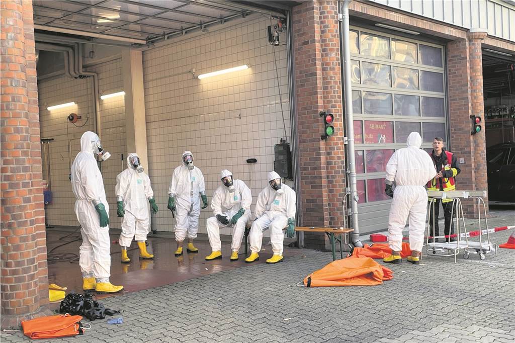 Suche nach Gefahrstoffen und Waffen: SEK-Einsatz in Herten – Polizei zieht Bilanz Einsatzkräfte in Schutzanzügen stehen im Innenhof der Feuerwache in Herten-Mitte.