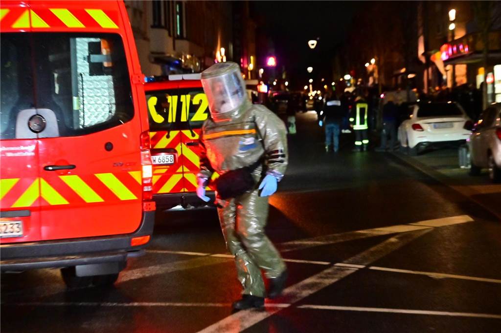 Einsatzkräfte in Spezialkleidung gehen in die Wohnung, aus der die beiden Männer abgeführt wurden. Sie vermuten dort auf gefährliche Giftstoffe zu treffen.