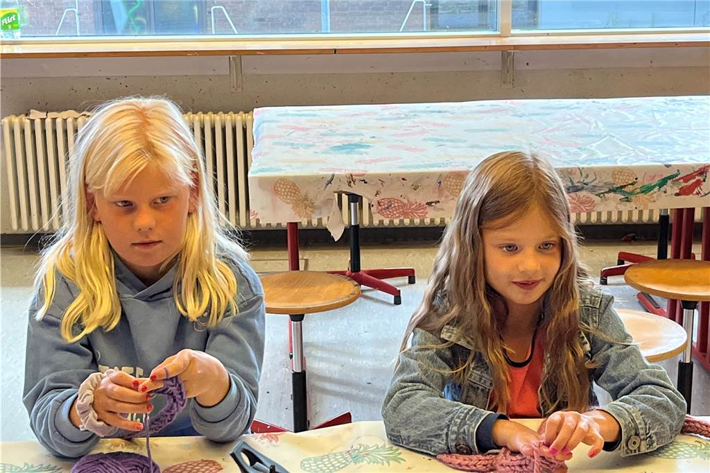 Emily und Lia arbeiten mit Wolle. Daraus soll ein Kuschelkissen werden.