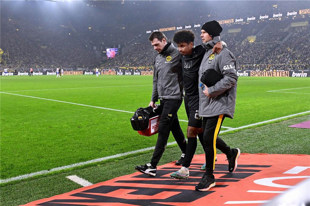 BVB-Profi Adeyemi fehlt verletzungsbedingt im DFB-Aufgebot: Ist der Vorbereitungsstart in Gefahr? Karim Adeymi wird vom BVB-Mannschaftsarzt und einem Betreuer gestützt.