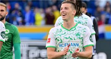 Tobias Raschl klatscht lächelnd in die Hände.