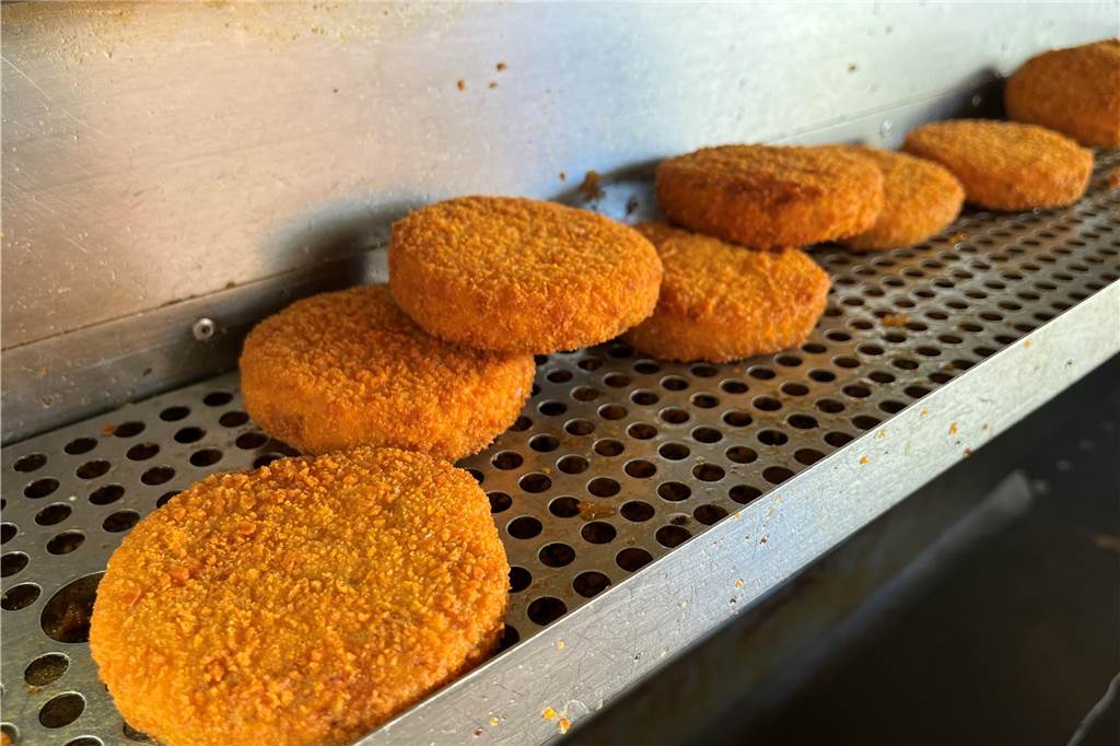 Fischfrikadellen liegen auf einer Fritteuse.