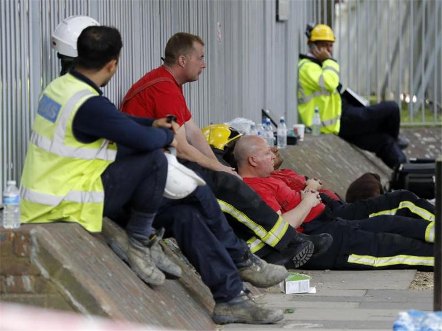 Zwölf Tote bei Feuerdrama in Londoner Hochhaus Erschöpfte Rettungskräfte machen am Rande des ausgebrannten Hochhauses eine Pause. Foto: Frank Augstein