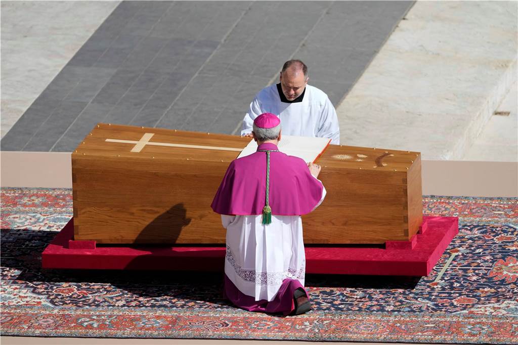 Jetzt live: Trauerfeier für Papst Franziskus beginnt: Sarg vor Altar aufgestellt Erzbischof Diego Giovanni Ravelli, mit dem Rücken zur Kamera, kniet neben dem Sarg von Papst Franziskus auf dem Petersplatz im Vatikan.