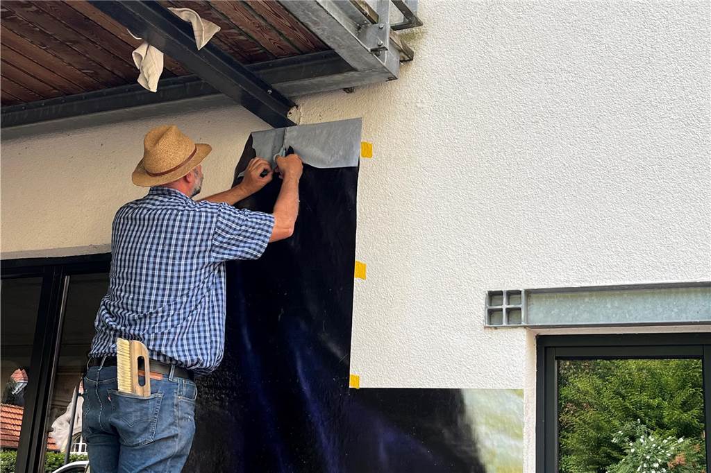 Steffen Mittelsdorf klebt ein Stück Foto-Kolaage an die Wand.