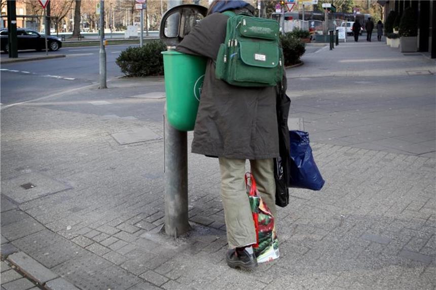 Es gibt Armut in Deutschland: Ein Mann sucht in der Düsseldorfer Innenstadt in einem Mülleimer nach verwertbarem Material. Foto: Martin Gerten