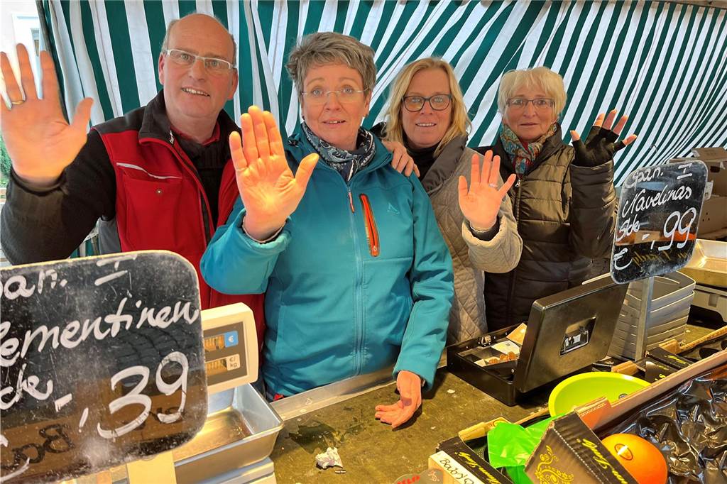 Markthändler Michael Hubracht und sein Team winken an ihrem Stand zum Abschied.