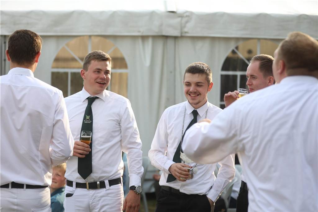 Junge Männer stehen in der Runde und trinken bekustigt ein Bier. 