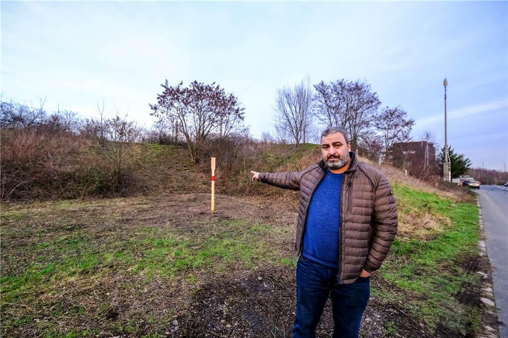 Nach dem Zugunglück: Vater berichtet über Reha-Beginn seines Sohns Amir Fadi El-Jaddouh, der Vater des bei einem Zugunglück in Recklinghausen schwer verletzten 9-Jährigen, zeigt auf einen Wall, hinter dem Bahngleise liegen.