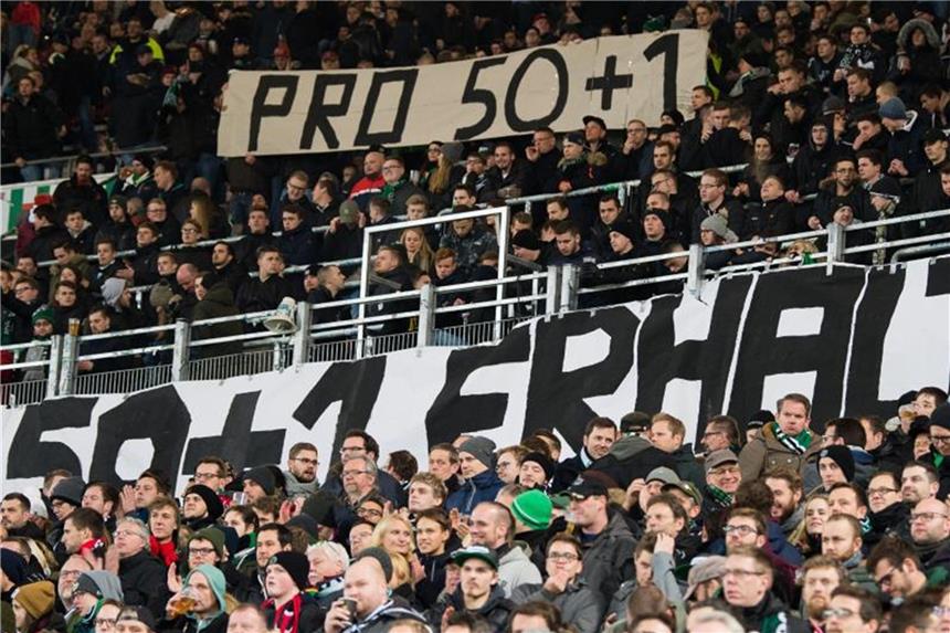 Fans von Hannover zeigen Plakate mit der Aufschrift "Pro 50+1". Foto: Swen Pförtner