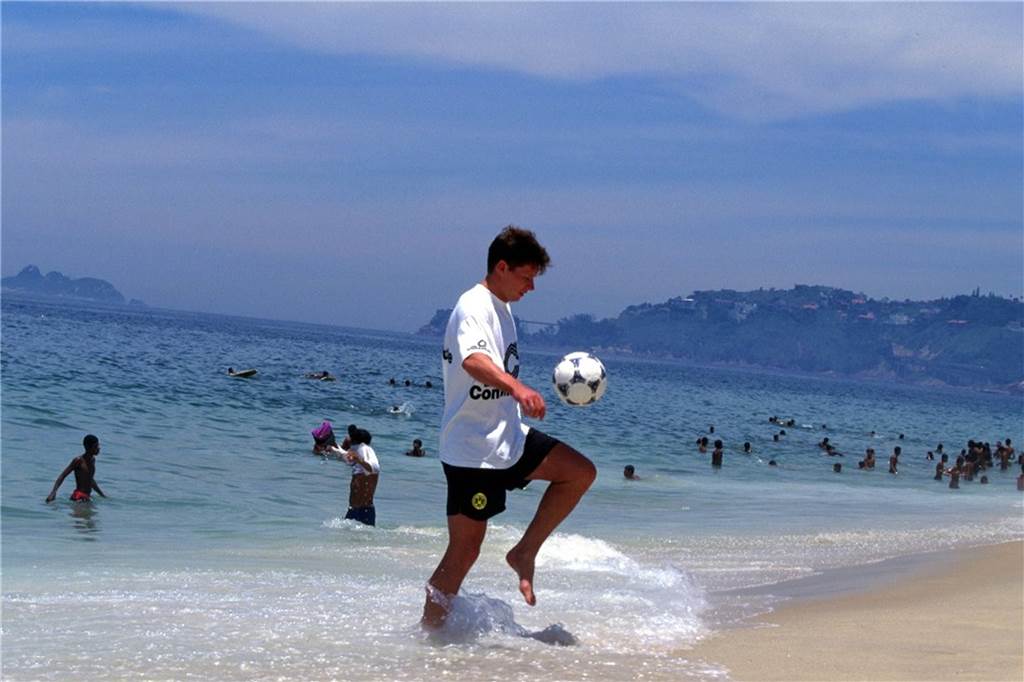 Stefan Reuter hält den Ball am Strand hoch.