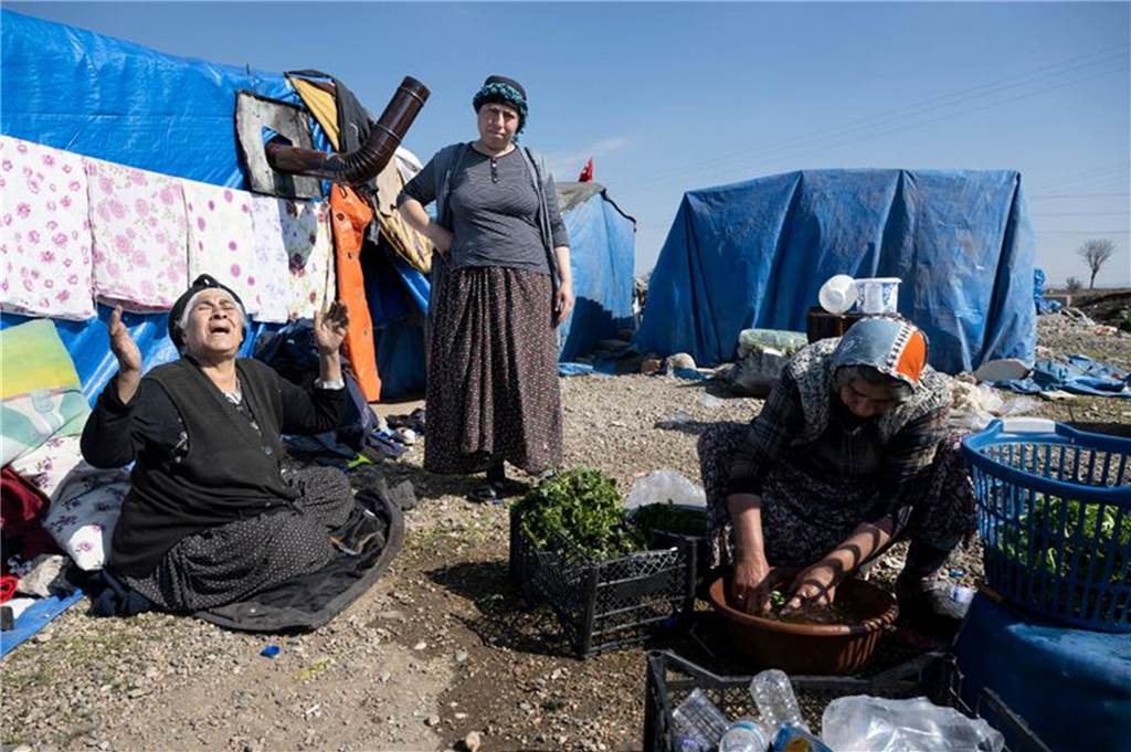 Ein Monat nach schwerem Beben in Syrien und Türkei: „Die Zukunft ist vorbei“ Frauen bereiten in einem provisorischen Zeltlager am Straßenrand in Kirikhan Essen zu.