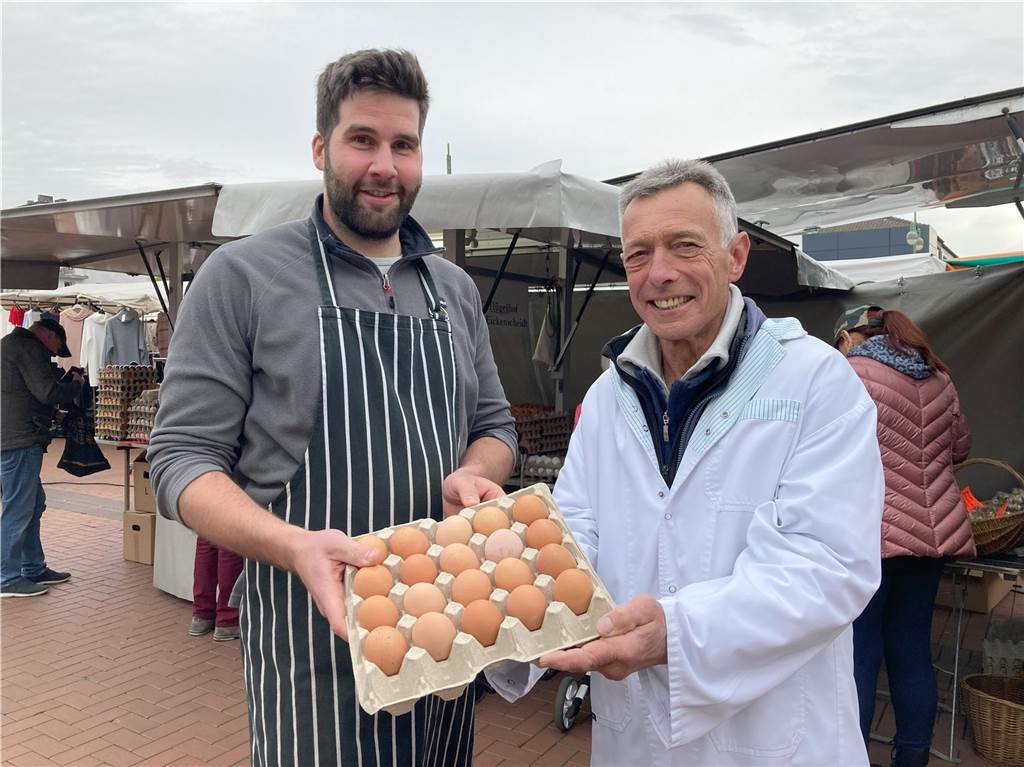 Mister und Misses Wochenmarkt hören nach 42 Jahren auf: „Ära geht zu Ende“ Felix Bontrup (links) und Klaus Eickenscheidt halten vor einem Stand auf dem Wochenmarkt Waltrop eine große Papp-Palette mit braunen Hühnereiern in den Händen.