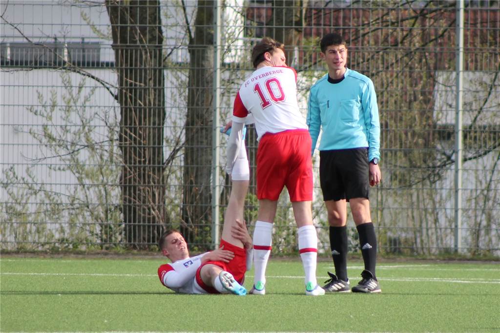 Zwei grundverschiedene Hälften: Overberge zittert sich zum Derbysieg gegen TuRa (Spielanalyse) Felix Evers mit Krampf verletzt am Boden. Henri Wittwer kümmert sich. Beide trafen jeweils einmal für den FCO. Daneben steht Schiedsrichter Mertcan Sahin.