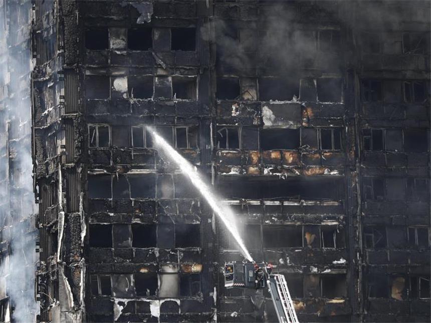 Zwölf Tote bei Feuerdrama in Londoner Hochhaus Feuerwehrleute spritzen Wasser auf das immer noch qualmende Hochhaus. Foto: Tolga Akmen