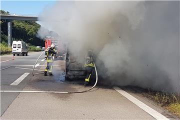 Feuerwehrmänner mit Atemschutzmasken löschten den Fahrzeugbrand auf der A45. Kurzzeitig gab es Verkehrsbehinderungen.