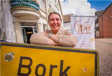 Figan Ucar-Macit mit dem Logo des von ihr mitgegründeten Vereins „Schicksalshelfer“ vor der Dorfkneipe in Selm-Bork, die sie mit ihrem Mann als Dorf-Treffpunkt ebenfalls am Leben erhält.