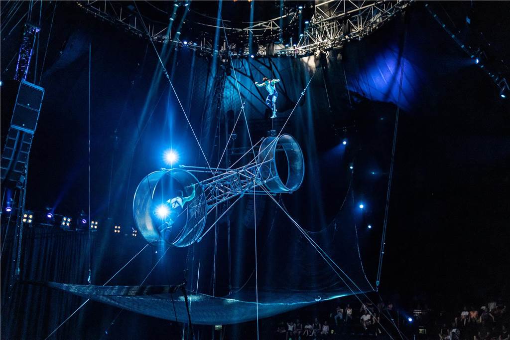 Spektakel in Dortmund: Flic Flac Weihnachtszirkus wieder da Eine Metallwippe mit zwei großen Ringen schwebt in der Luft. Auf jeder Seite steht ein Artist. Der Linke steht auf seiner Seite in dem Ring, während der rechte Artist gerade mit dem Schwung der Wippe hochspringt.