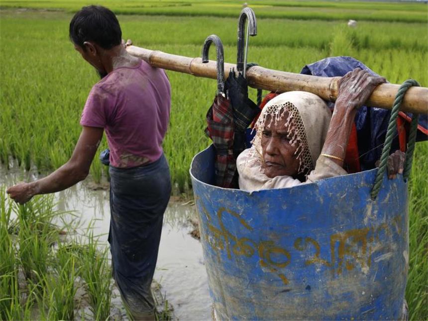 UN sehen ethnische Säuberung in Myanmar Flüchtlinge der Rohingya tragen eine alte Frau über einen schlammigen Weg, nachdem sie die Grenze zwischen Bangladesch und Myanmar überquert haben. Foto: Md. Mehedi Hasan/Pacific Press via ZUMA Wire