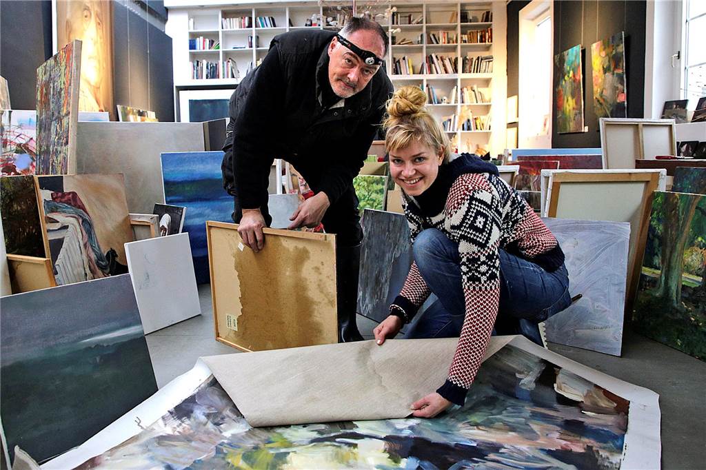 Frank Burkamp und Maike Prause begutachten die Wasserschäden, die an den Bildern entstanden sind.