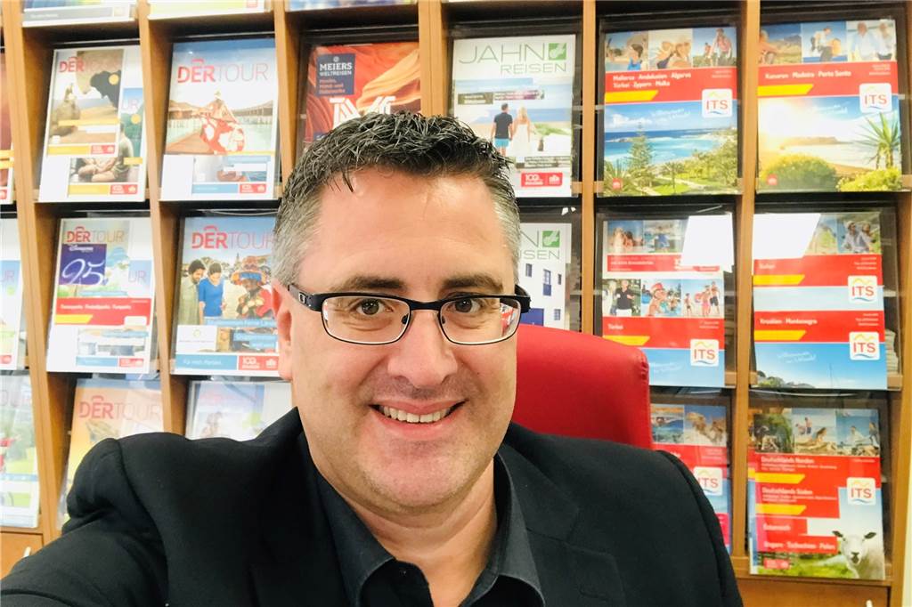 Reiseexperte Christopher Wrobel: „Preisentwicklung ist auf Dauer nicht gut“ Frank Herbrechter sitzt vor einem Regal mit vielen Reisemagazinen.