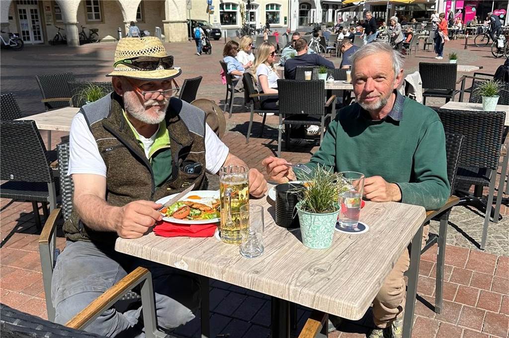 Zwei Männer sitzen am Tisch und essen.