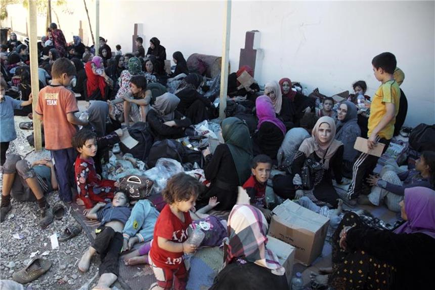 Helfer fordern mehr Schutz für minderjährige Flüchtlinge Frauen und Kinder sitzen im Irak an einem Sammelpunkt für vertriebene Menschen. Für minderjährige Flüchtlinge ist der Weg nach Europa besonders gefährlich. Foto: Balint Szlanko