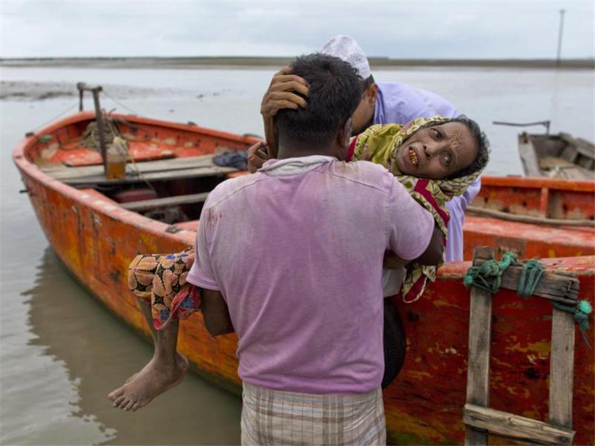 Freiwillige helfen in Teknaf (Bangladesch) einer älteren Rohingya-Frau, die aus Myanmar geflüchtet ist. Foto: Gemunu Amarasinghe