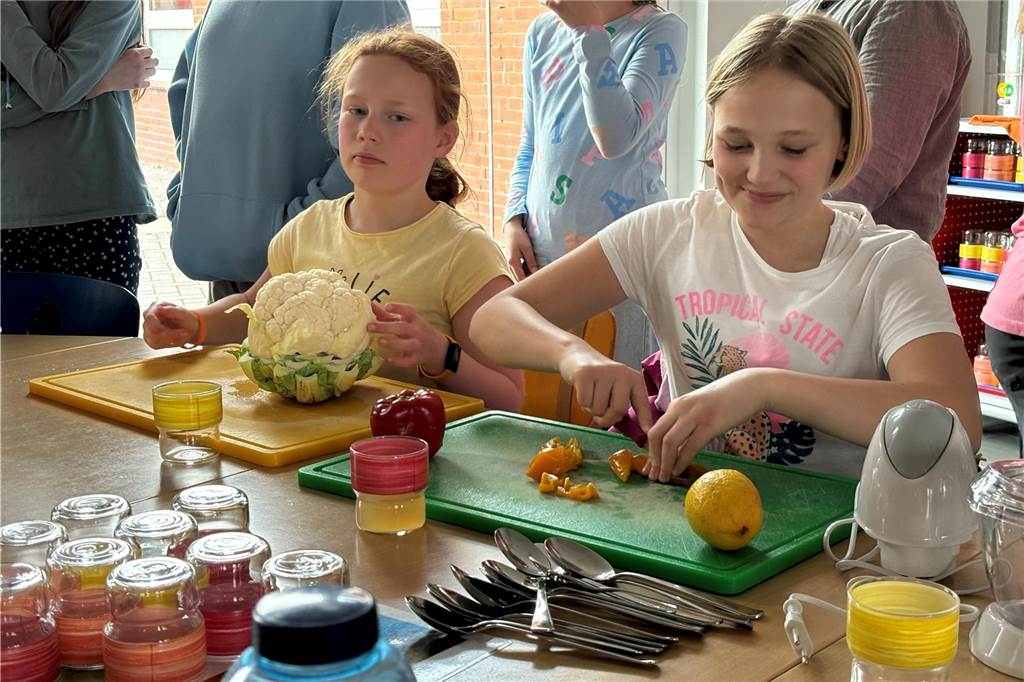 Uhlandschule gewinnt Bundes-Wettbewerb: Star-Koch Holger Stromberg kocht Frieda Marike Neumann (l.) und Pauline Josefin Bömken aus der 4e beim Schneides des Gemüses.