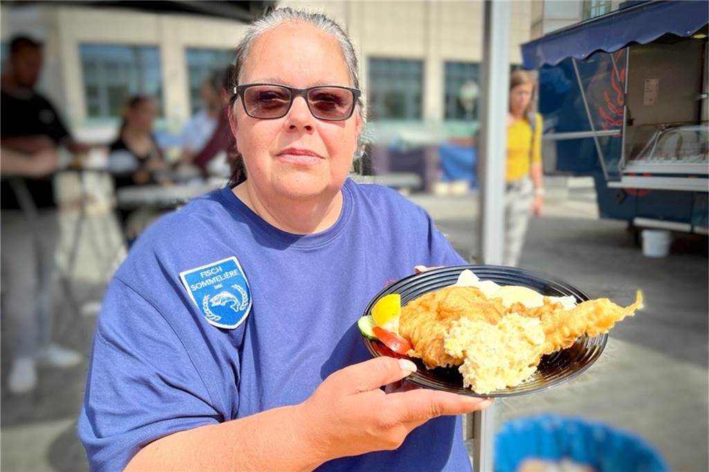 Andrea (53) ist Dortmunder Urgestein vom Wochenmarkt: „Wir brauchen ganz sicher keinen Kerl.“ Andrea Niesel zeigt vor ihrem Fischstand auf dem Dortmunder Wochenmarkt einen Teller mit Backfisch.