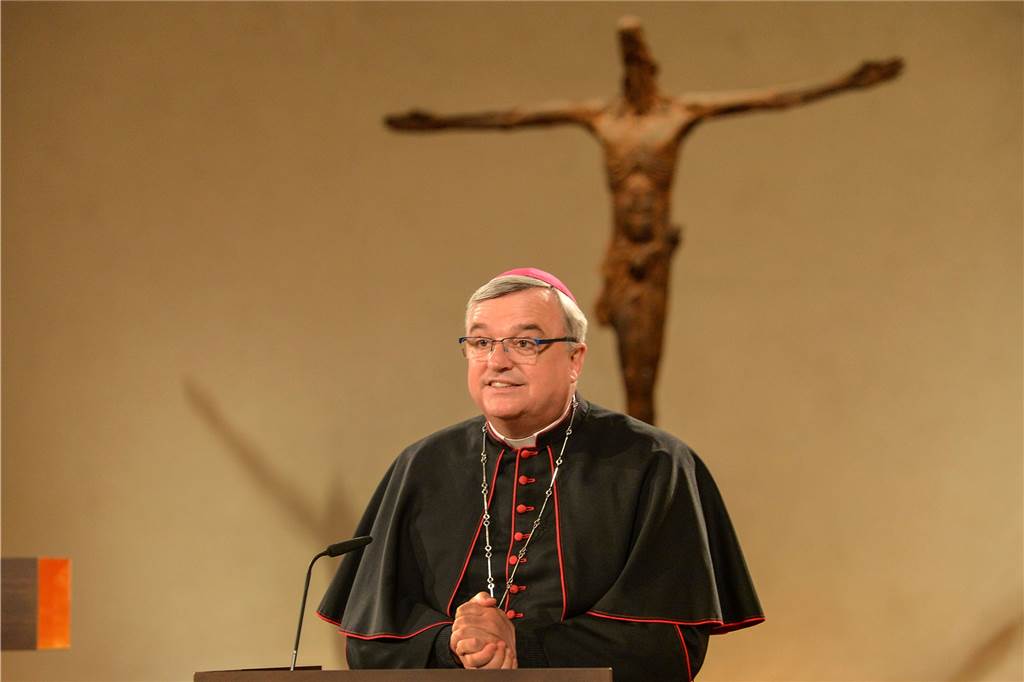 Bischof Karl-Heinz Wiesemann steht in der Kirche an der Kanzel und hat die Hände gefaltet.