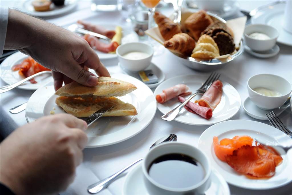 Bäcker an Weihnachten 2023: Öffnen sie in NRW an Heiligabend und den Feiertagen? Ein Mann schneidet am Frühstückstisch ein Brötchen auf.