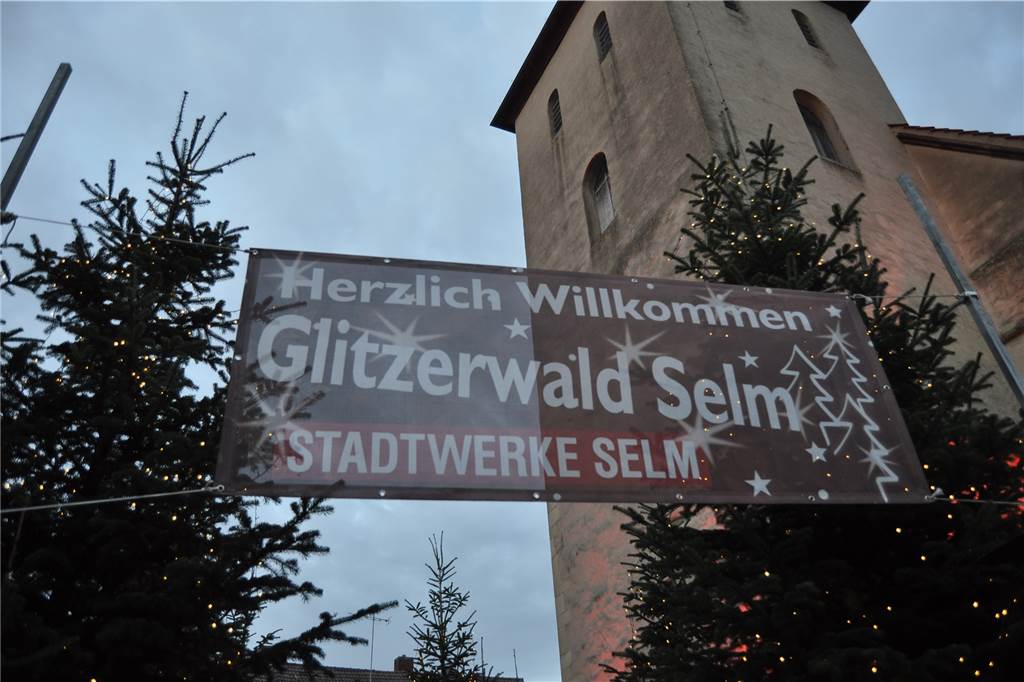 Warum wurde Glitzerwald 2022 abgesagt? Stadt rechtfertigt Entscheidung Vor der Friedenskirche in Selm hängt ein großes Banner mit der Aufschrift "Herzlich willkommen - Glitzerwald Selm".