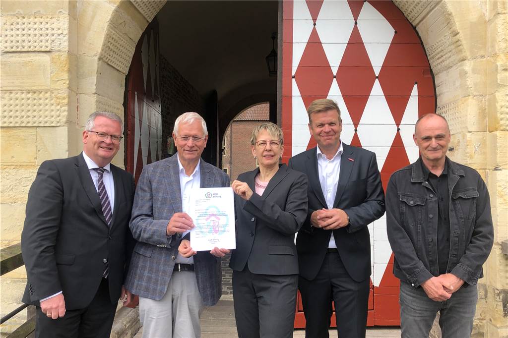 Eberhard Berg: Vorburgtor überraschte die Handwerker bei Restaurierung Menschen stehen vor dem Schloss-Tor mit einer Urkunde