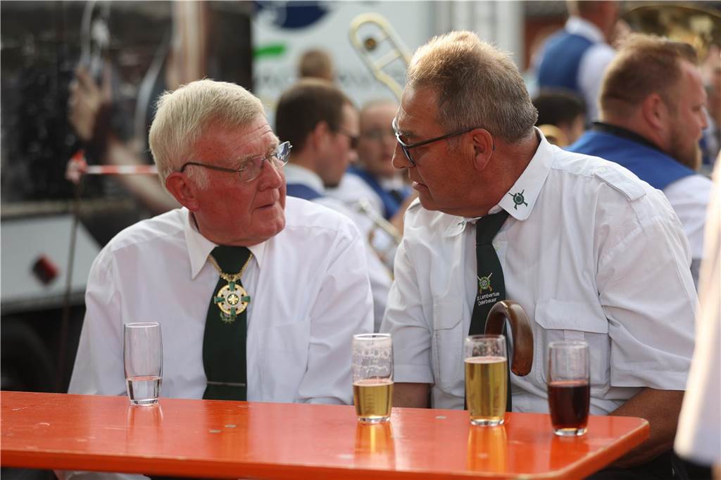 Zwei Männer sitzen auf einer Bank und schauen sich in die Augen. Auf dem Tisch steht Bier. 