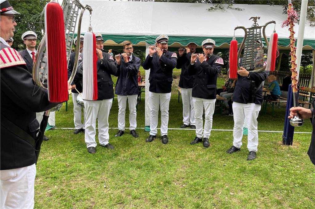 Die Musiker stehen in einer Reihe und spielen ihre Instrumente. 