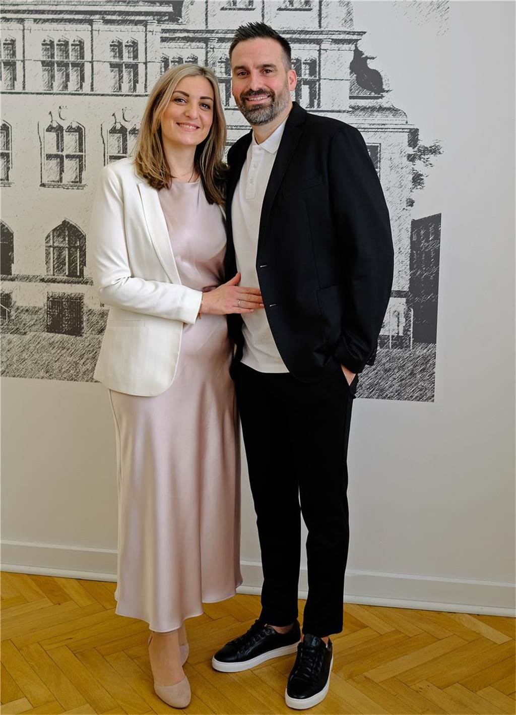 Stefanie Bumbic und Jesper Holtkamp stehen vor einem Foto des Recklinghäuser Rathauses.