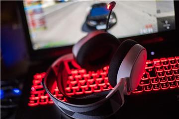 Gaming-Kopfhörer liegen auf einem Laptop, auf dem ein Rennspiel (Trackmania) gespielt wird. Foto: Lino Mirgeler/Archiv