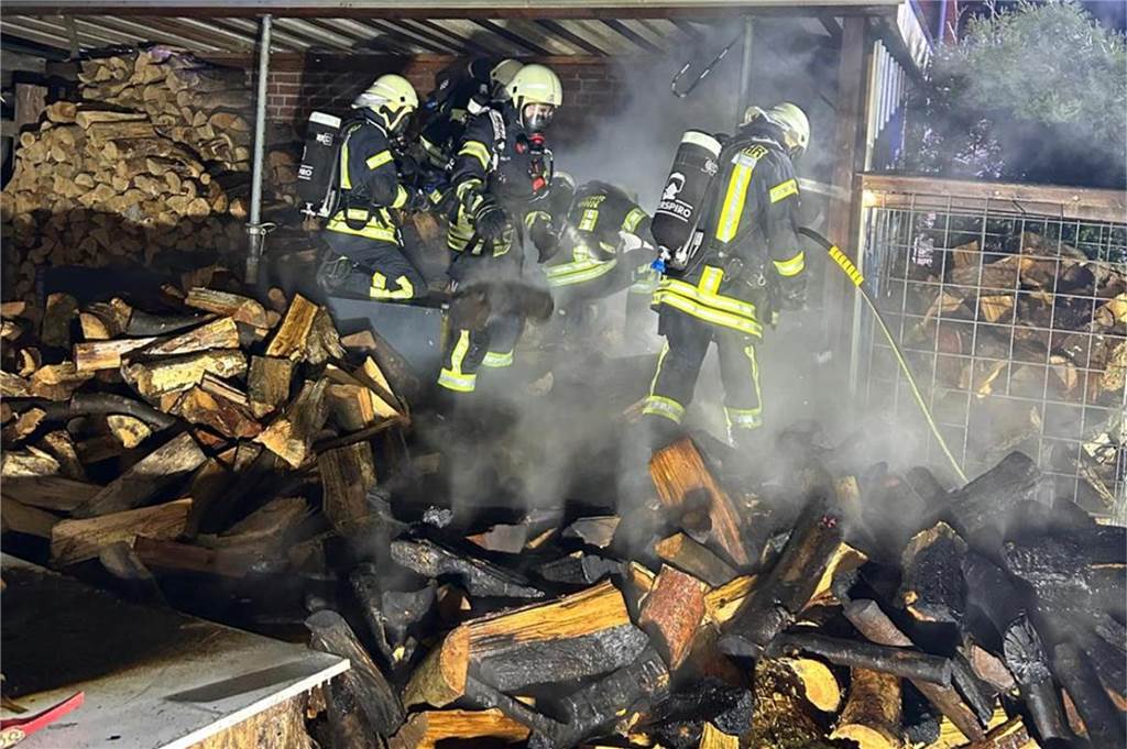 Feuerwehrleute löschen das Feuer in einem Holzunterstand