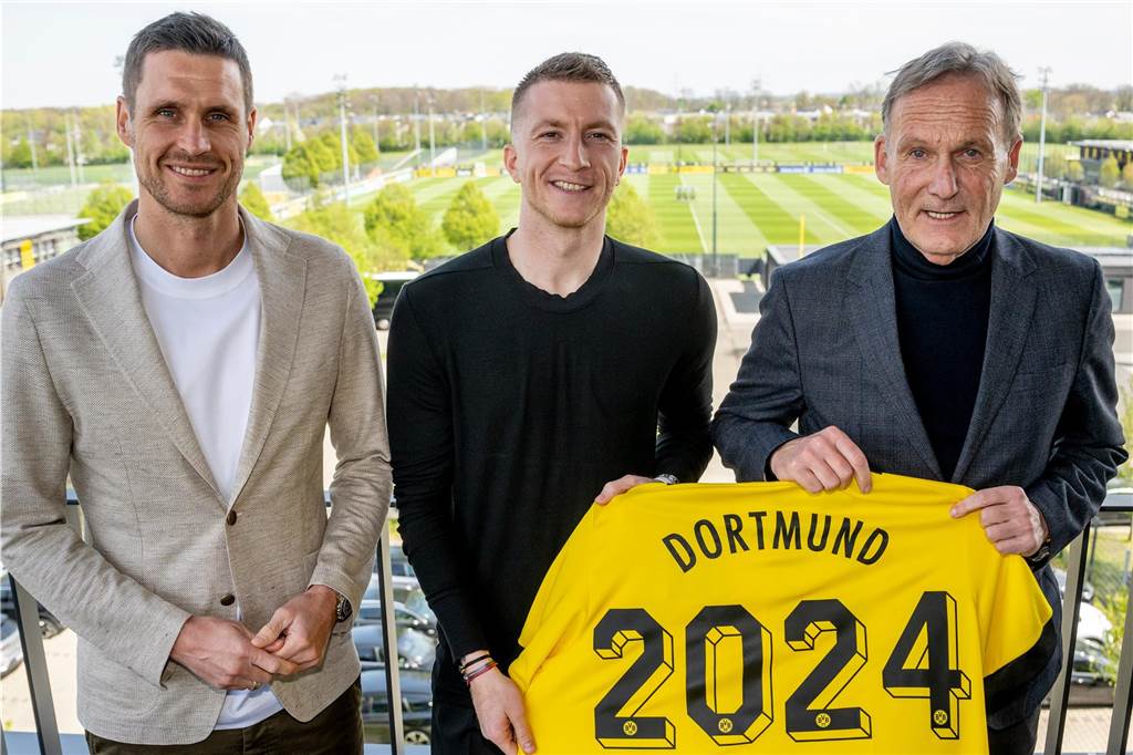 Marco Reus verlängert seinen Vertrag beim BVB: „Große Lust auf den Verein“ Sebastian Kehl, Marco Reus und Hans-Joachim Watzke halten ein Trikot in die Kamera.