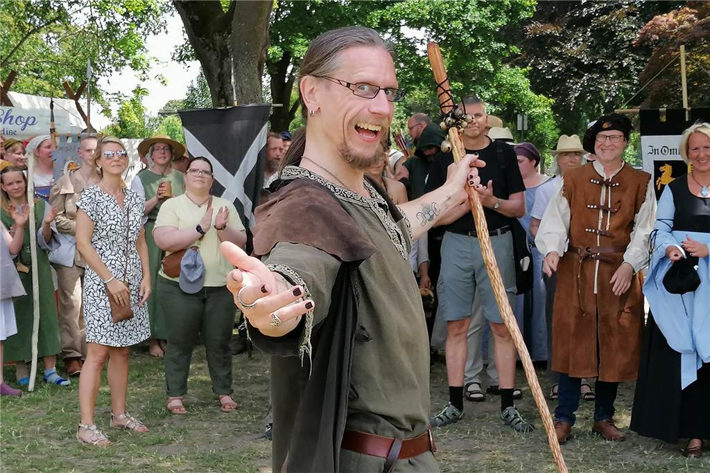 „Mittelalterliches Treyben zu Mengede“: Größeres Angebot für Kinder "Geschichten-Weber" Tandaniel Roling beim "Mittelalterlichen Treyben" im Juni 2022 im Mengeder Volksgarten. Im Hintergrund Vertreterinnen und Vertreter aus der Mengeder Politik und Wirtschaft.