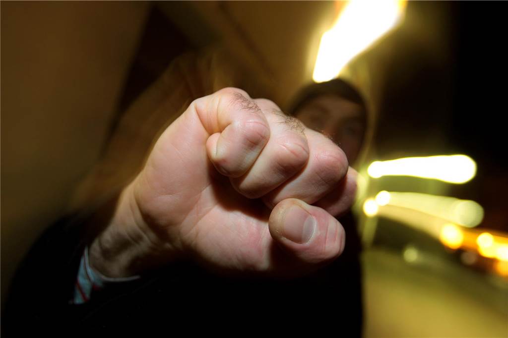 Maskierte Jugendliche verprügeln ein Kind und setzen Pfefferspray ein Ein junger Mann hebt seine geballte Faust.