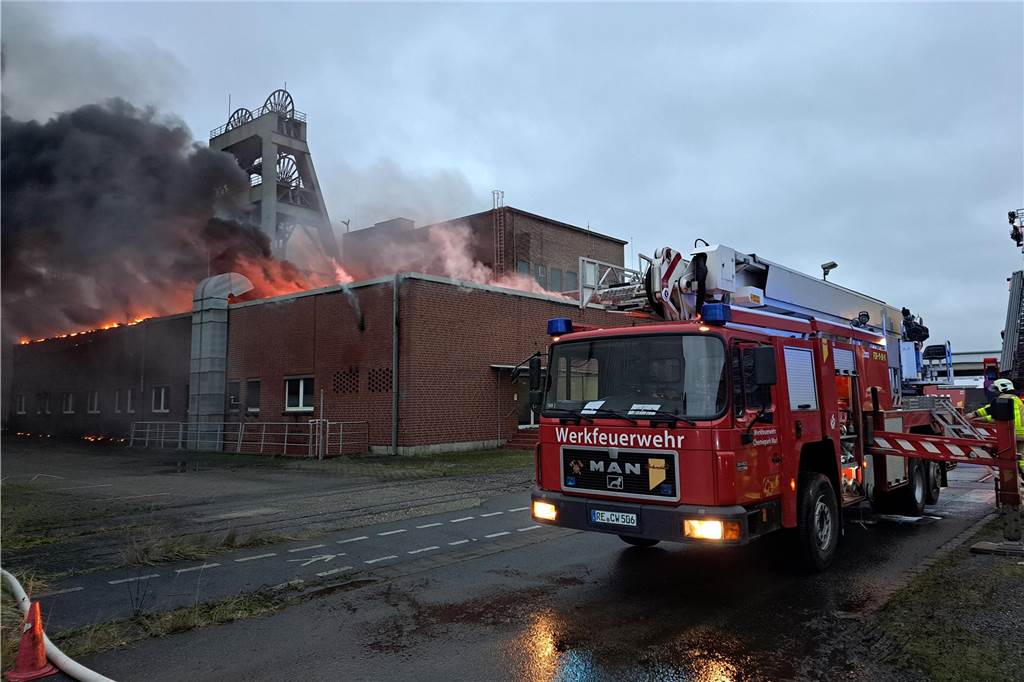 Großbrand auf AV 3/7: Bürogebäude brennt Ein Einsatzwagen der Feuerwehr steht vor einem brennenden Gebäude auf dem Gelände der ehemaligen Zeche Auguste Victoria (AV) in Marl.
