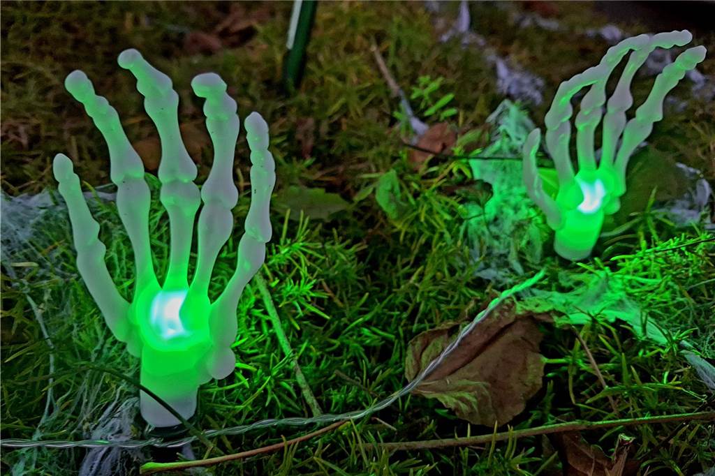 Grausiger Grusel: Familie Paß dekoriert ihr Haus für Halloween Grün illuminiert strahlen die Skeletthände in der Nacht vor dem Haus.