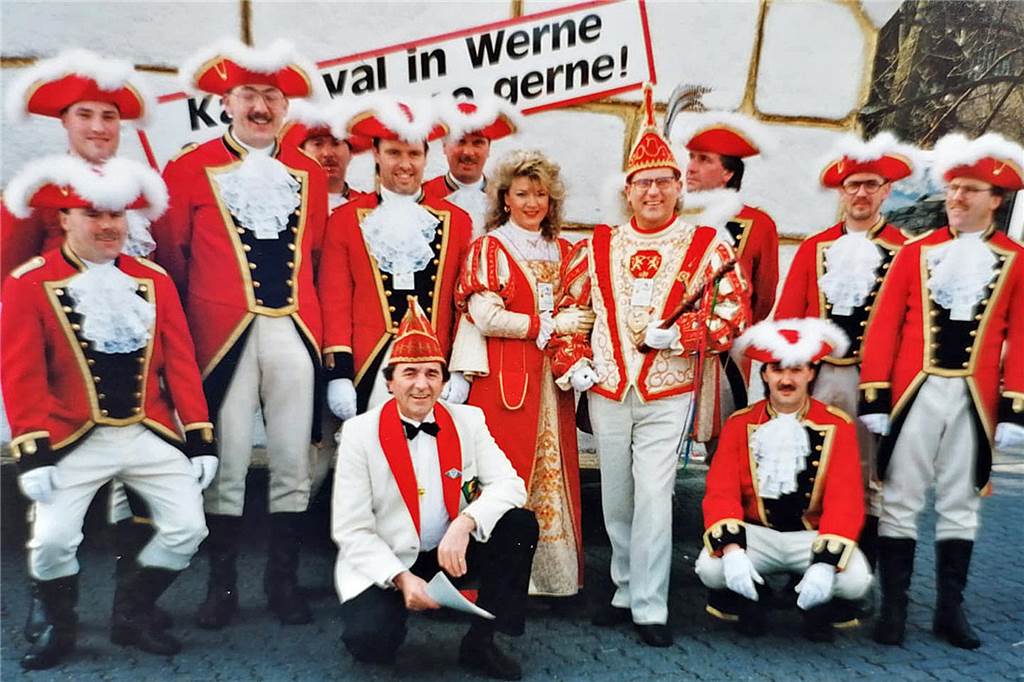 Mit einem Bollerwagen fing es an: 50 Jahre Rosenmontagszug und IWK Menschen stehen in Kostümen der Karnevalsgarde von Werne vor einer Hauswand.